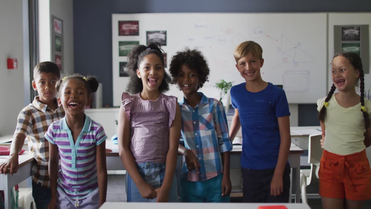 Video of happy diverse pupils jumping with joy in classroom