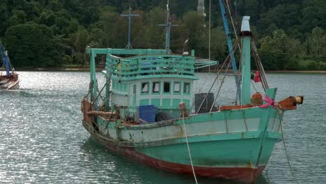 A-static-shot-of-2-old-fisherman-boats,-anchored-at-sea-near-an-island-Cropped