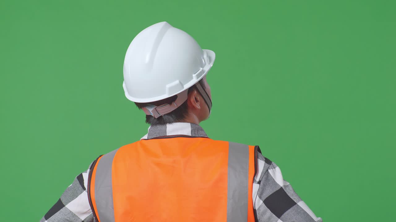 Close Up Back View Of A Male Engineer Wearing Safety Helmet Looking Around While Standing With Arms Akimbo In The Green Screen Background Studio