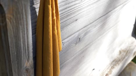 tilting shot down of an old rag hanging on a hook, which is hanging on an old wooden house