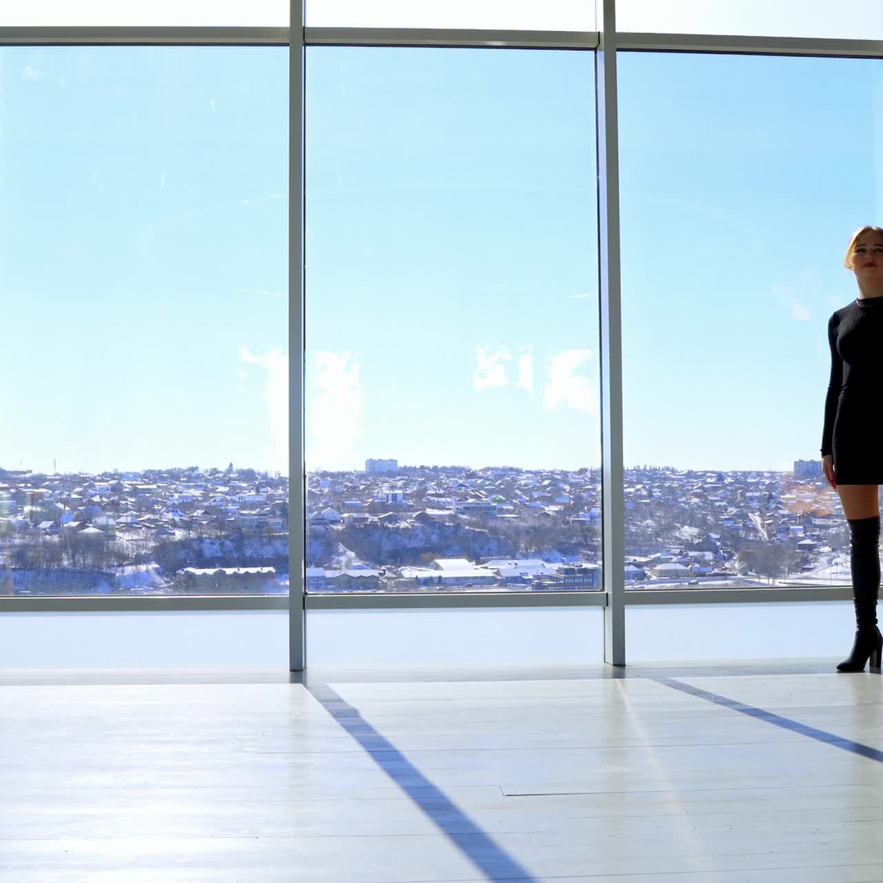 Beautiful young women walking in business center. Business women wearing elegant black talking in the light office with large windows with city landscape