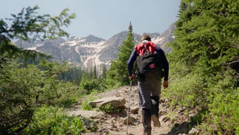 man hiking towards snowy mountains in summer | blue lakes trail, colorado