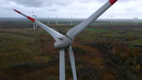 Aerial-shot-of-multiple-spinning-wind-turbines-for-renewable-electric-power-production-in-a-wide-rural-area-on-a-cloudy-day