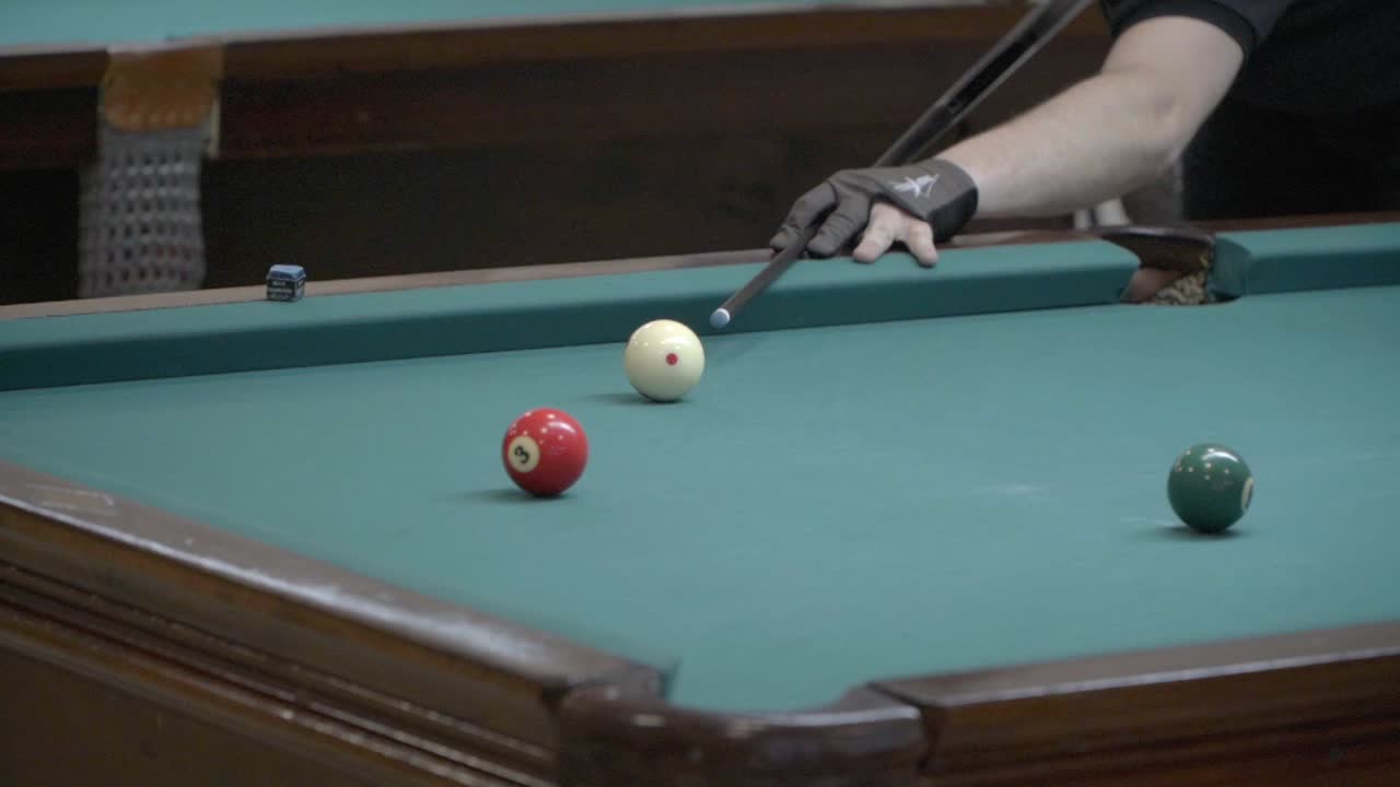 A player hammers a ball into a corner pocket during a pool game.