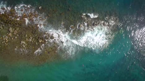 vista a volo d'uccello di un frangiflutti roccioso e onde che colpiscono contro di esso