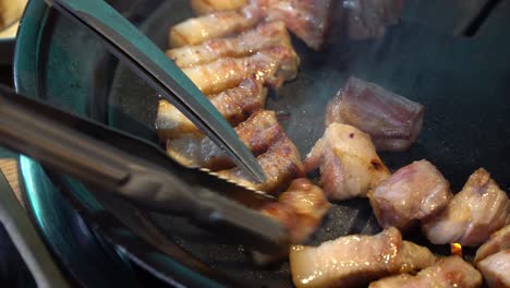 close up of fat pork belly sizzling on traditional korean grill