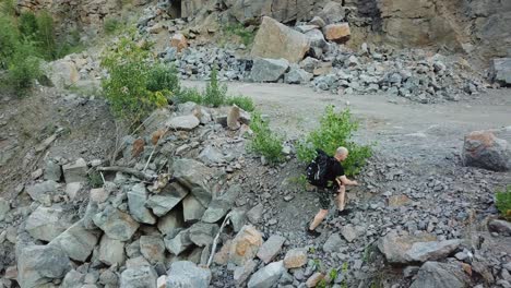 aerial view of a young man walking along a giant rocky mountain. traveler on the cliff. travel concept.