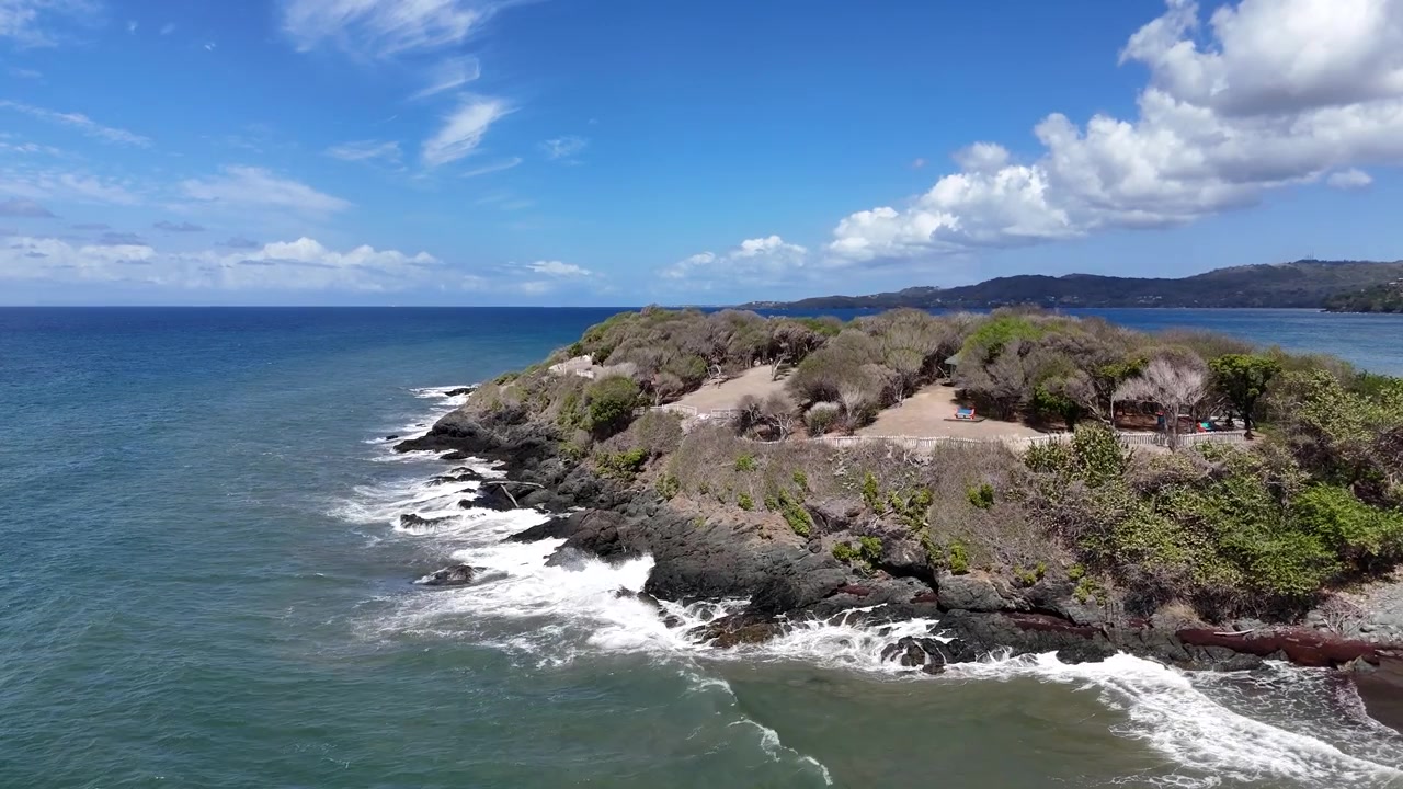 Vista aérea baja con dron de las escarpadas rocas volcánicas y el oleaje rompiendo en el Fuerte Granby. Paisaje costero cinematográfico del Mar Caribe y la Isla de Tobago en Trinidad y Tobago.
