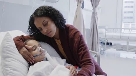 worried biracial mother and her sick daughter patient with oxygen mask in hospital in slow motion