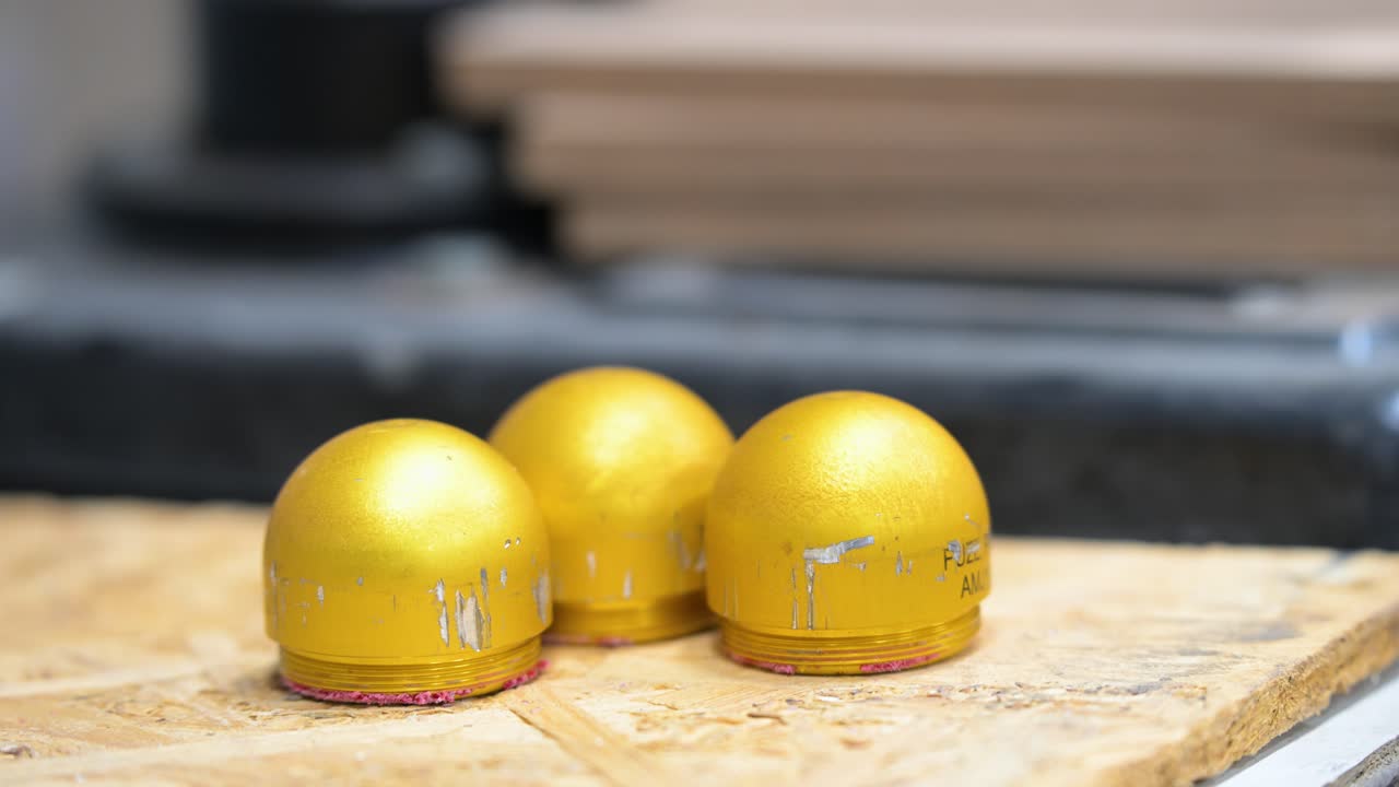 Three yellow grenade top casings, prepped for plastic modification and drone attachment, are seen at a workshop in Ukraine's Donetsk region. Showcasing adaptive weapon tech for modern warfare