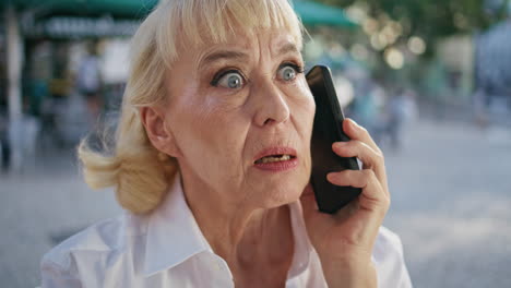 wrinkled lady speaking mobile phone on city street closeup. mature woman calling