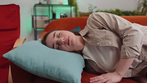 tired young woman girl lying down in bed taking a rest at home, napping, falling asleep on couch