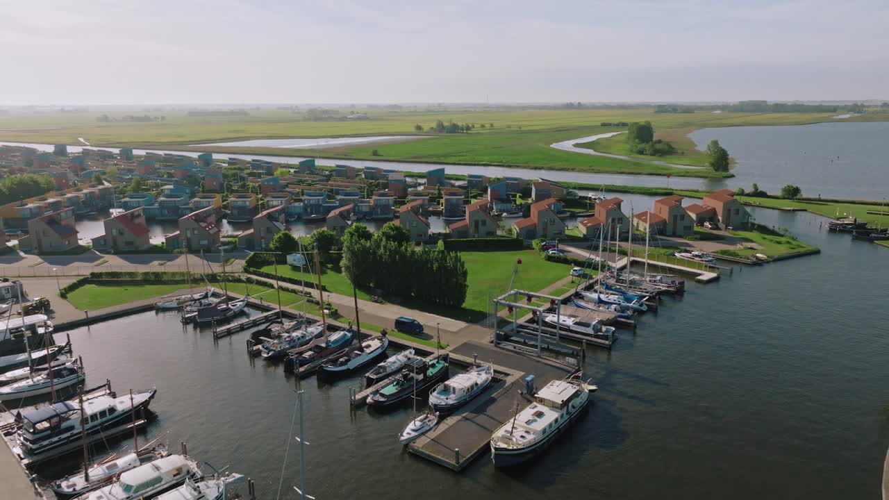 Aerial view zooming out reveals traditional boats and vacation houses in the picturesque Dutch town of Heeg