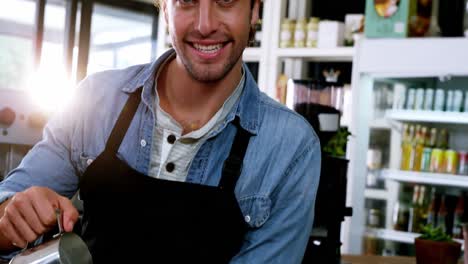 camarero sonriente haciendo una taza de café en el mostrador