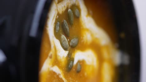 close-up of a bowl of creamy pumpkin soup with pumpkin seeds