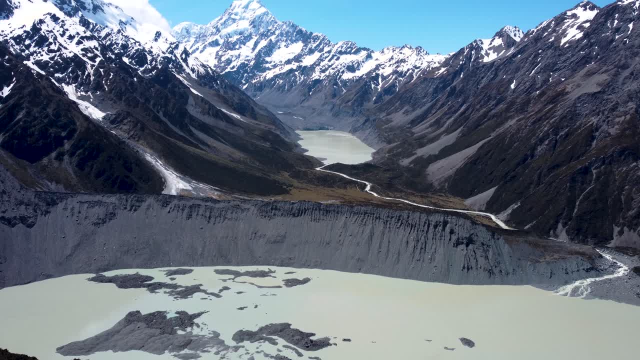 Drone reveal view snowy mountains, Hooker and Mueller lake on a clear sunny summer day in Mount Cook National Park, New Zealand.