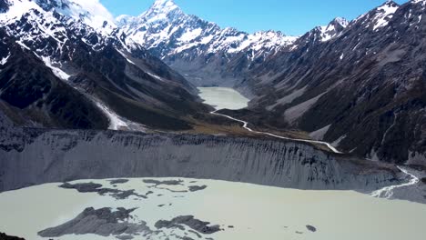 drone reveal view snowy mountains, hooker and mueller lake on a clear sunny summer day in mount cook national park, new zealand.