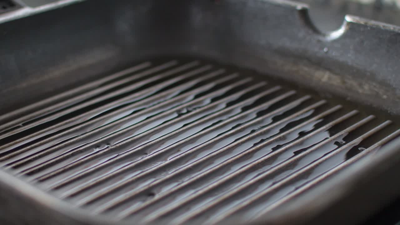 Hand places lamb chops on a grilled pan filled with olive oil
