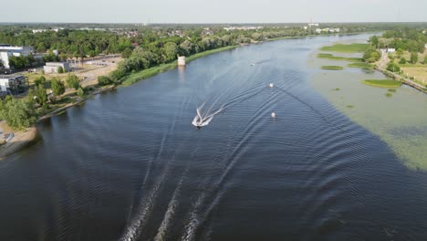 Motorboats-ply-dark-surface-of-natural-river-in-city-of-Parnu,-Estonia