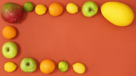 tropic summer frame made of exotic fruits ordering on orange background. stop motion