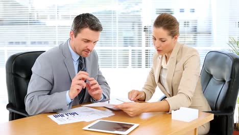 Business-team-looking-at-documents-together-at-desk