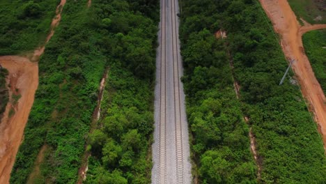 jib down aerial of a long railroad running through nature in rural nigeria, africa