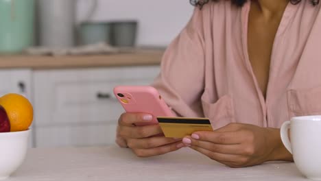 woman paying with credit card on a mobile device in a kitchen