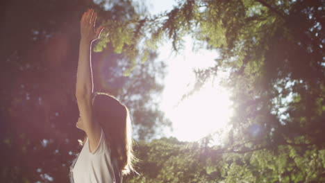 Young-Caucasian-cheerful-woman-in-glasses-spinning-around-with-hands-up-in-the-park-on-a-summer-day