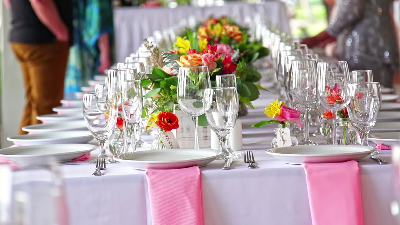 Table de fête dressée avec des assiettes, des verres et des centres de table fleuris