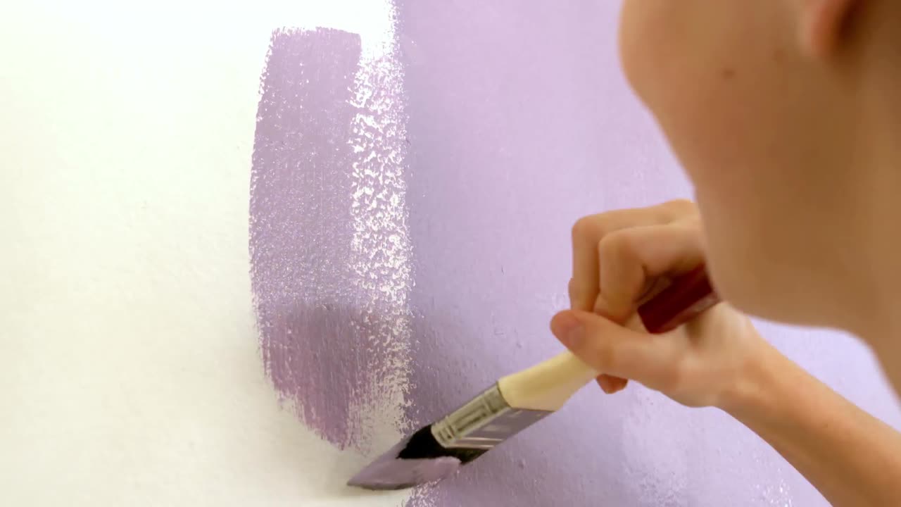 chica redecorando una pared de la habitación con el pincel