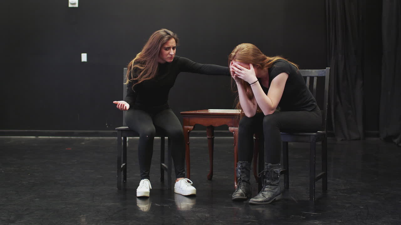 To kvinnelige dramastudenter ved en scenekunstskole i en improvisasjonsklasse i studio som fremfører en scene.