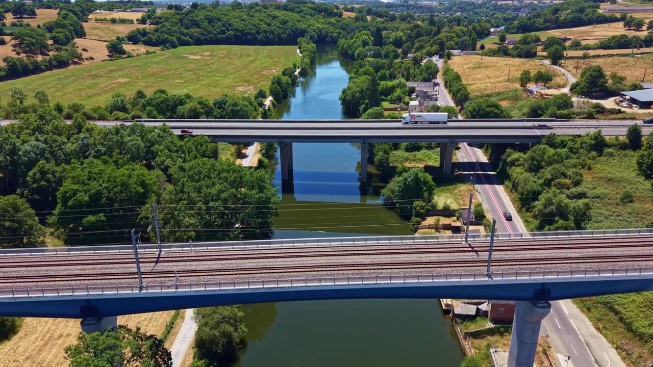 Vista aérea de veículos atravessando pontes rodoviárias e ferroviárias sobre um rio na França rural
