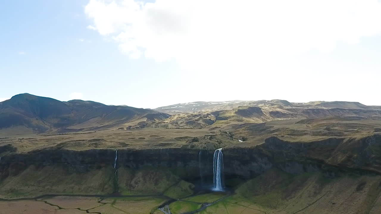 disparo de drones elevándose por encima de la cascada de la montaña de islandia