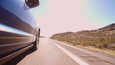 vista de ángulo bajo de un coche conduciendo a lo largo de una carretera de campo tomada en r3d