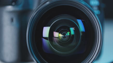 Camera-lens-reflecting-colors-in-refraction-on-table,-black-background