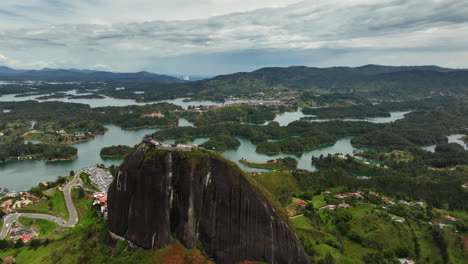 drone shot over the el peñón rock, toward the reservoir, in cloudy guatape, colombia