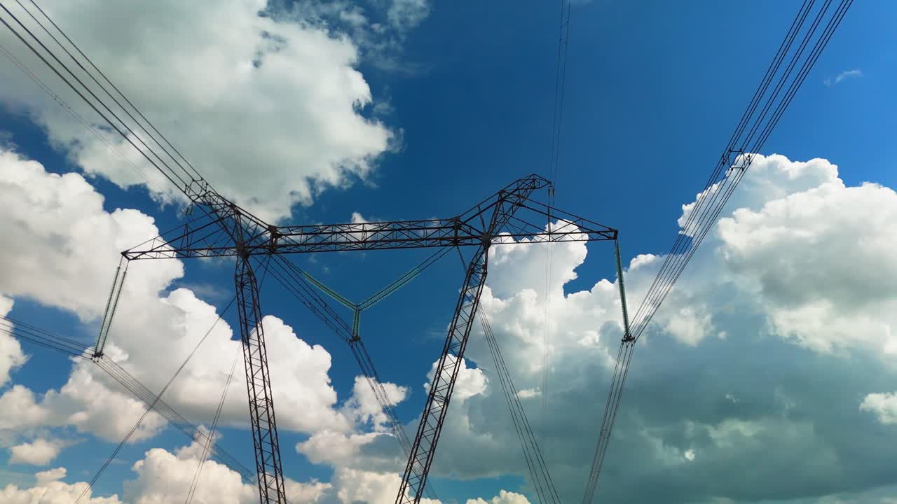 High Voltage Power Lines and Pylons Against Blue Sky with Clouds