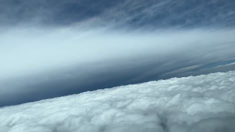Aerial-shot-from-a-jet-cockpit-while-flying-through-an-almost-unrealistic-sky-with-the-perfect-anvil-shape-of-a-huge-cumulonimbus-ahead,-during-a-right-turn