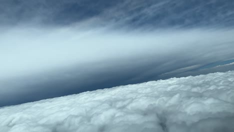 disparo aéreo desde una cabina de un avión mientras vuela a través de un cielo casi irreal con la forma perfecta de yunque de un enorme cumulonimbus por delante, durante un giro a la derecha