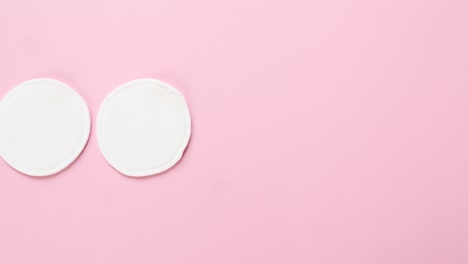 las mujeres jóvenes ponen almohadillas de algodón orgánico sobre un fondo rosa. cero residuos, reutilizables, ecológicos, removedores de maquillaje y concepto de lavado. patrón, luz dura, vista superior.