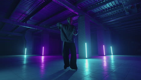 eine stahlfrau tanzt hip-hop-freestyle in modernem stil in einer halle mit neonlicht in lila-blauen farben. professionelle hip-hop-tänzerin
