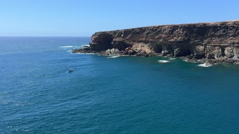 wide shot of the expansive volcanic coastline and cliffs of ajuy, with the deep blue atlantic ocean stretching to the horizon. fuerteventura, canary islands, spain