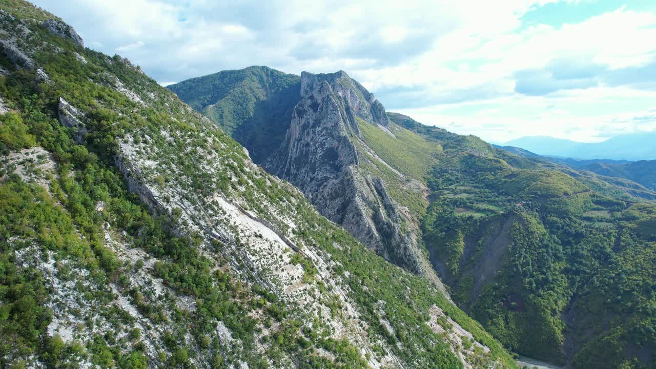 Aerial shot (dolly and tracking) flying over Kabashi village. It shows houses and structures surrounded by the vast and rugged Albanian mountainous landscape