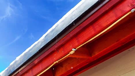 Close-up-slo-mo-shot-of-water-droplets-dripping-off-a-roofline-from-melting-snow