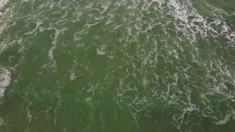 cornwall polly joke drone tilt shot looking down at seawaves in cornish coast, uk