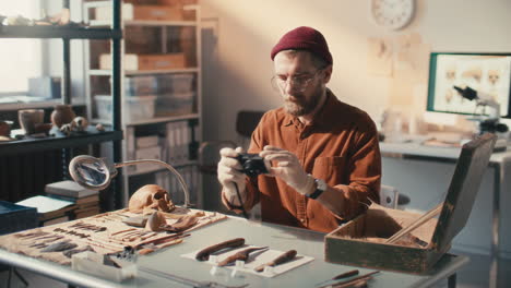 archaeologist placing labels and documenting artifacts with camera in lab