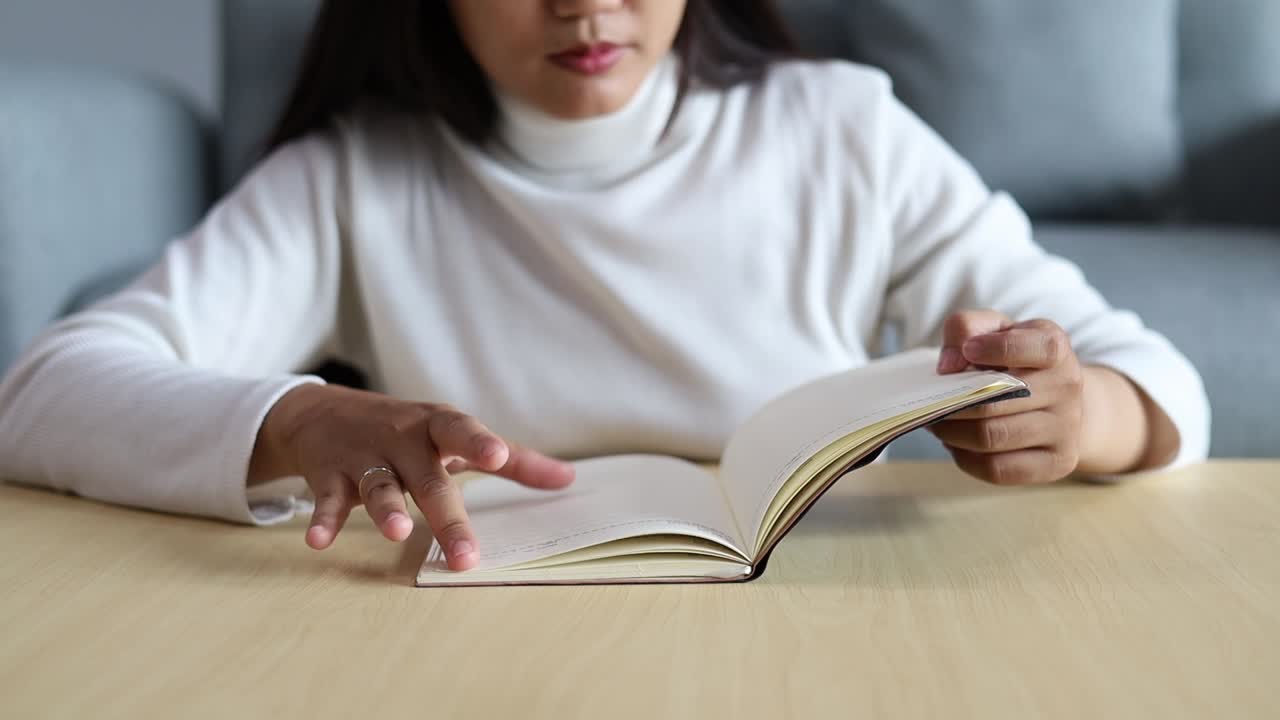 Close-up of Asian Woman reading book, hands turning page book