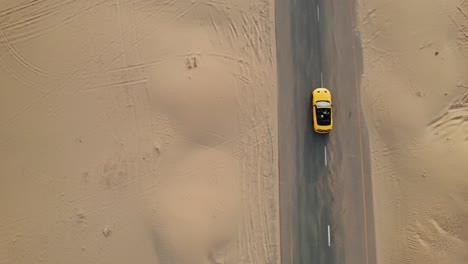 coche convertible amarillo conduciendo en una carretera a través del desierto