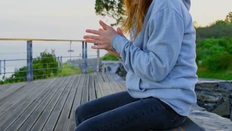 Side-view-of-young-caucasian-female-skateboarder-sitting-on-skateboard-at-observation-point-4k