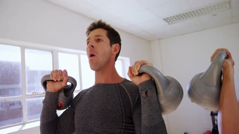 hombre y mujer haciendo ejercicio con kettlebell 4k